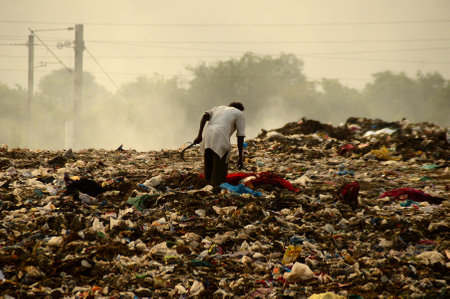 AMRAVATI, MAHARASHTRA, INDIA - APRIL 09, 2014: Unidentified rag pickers search for recyclable material in the garbage. Land and air pollution in India on April 09, 2014, Amravati, India.のeditorial素材