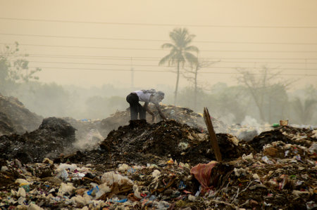 AMRAVATI, MAHARASHTRA, INDIA - APRIL 09, 2014: Unidentified rag pickers search for recyclable material in the garbage. Land and air pollution in India on April 09, 2014, Amravati, India.のeditorial素材