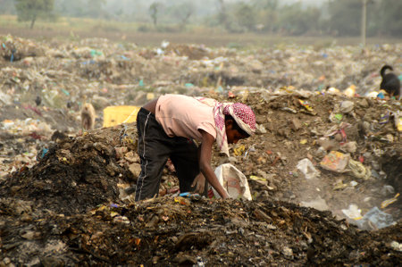 AMRAVATI, MAHARASHTRA, INDIA - APRIL 09, 2014: Unidentified rag pickers search for recyclable material in the garbage. Land and air pollution in India on April 09, 2014, Amravati, India.のeditorial素材