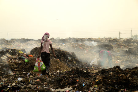 AMRAVATI, MAHARASHTRA, INDIA - APRIL 09, 2014: Unidentified rag pickers search for recyclable material in the garbage. Land and air pollution in India on April 09, 2014, Amravati, India.のeditorial素材