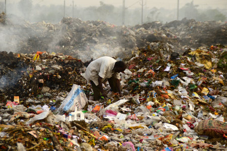 AMRAVATI, MAHARASHTRA, INDIA - APRIL 09, 2014: Unidentified rag pickers search for recyclable material in the garbage. Land and air pollution in India on April 09, 2014, Amravati, India.のeditorial素材