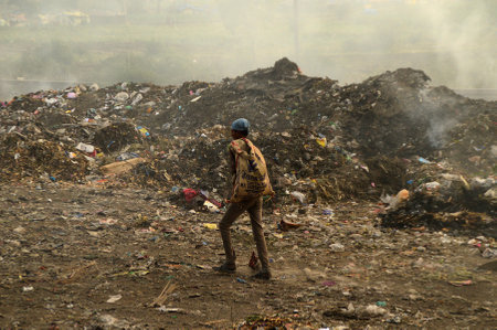 AMRAVATI, MAHARASHTRA, INDIA - APRIL 09, 2014: Unidentified rag pickers search for recyclable material in the garbage. Land and air pollution in India on April 09, 2014, Amravati, India.のeditorial素材