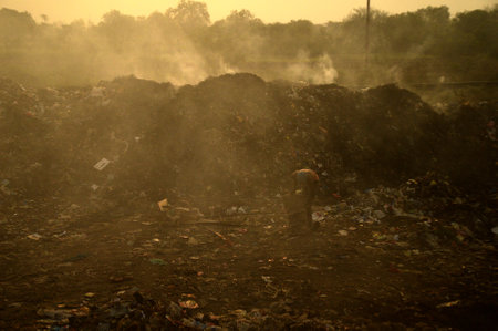 AMRAVATI, MAHARASHTRA, INDIA - APRIL 09, 2014: Unidentified rag pickers search for recyclable material in the garbage. Land and air pollution in India on April 09, 2014, Amravati, India.のeditorial素材