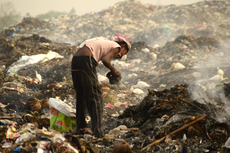 AMRAVATI, MAHARASHTRA, INDIA - APRIL 09, 2014: Unidentified rag pickers search for recyclable material in the garbage. Land and air pollution in India on April 09, 2014, Amravati, India.のeditorial素材