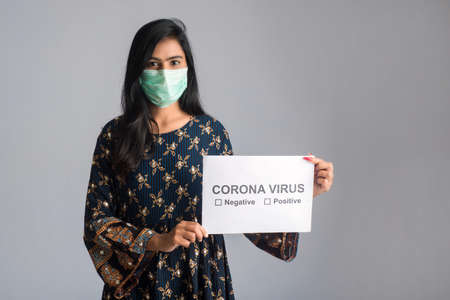 A young woman in a medical mask holding a board of the epidemic of Coronavirus, Covid-19の写真素材