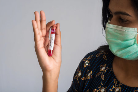 Young girl holding a test tube with blood sample for coronavirus or 2019-nCoV analyzing.