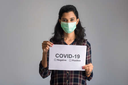 A young woman in a medical mask holding a board of the epidemic of Coronavirus, Covid-19の写真素材