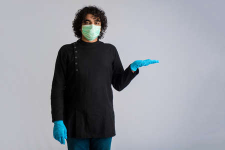 Young man wearing a medical face mask Showing something on hand. a man wearing a surgical mask for protection from coronavirus.の写真素材