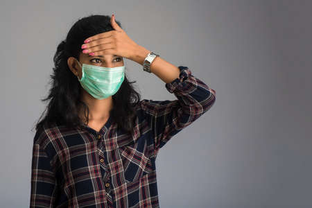 Beautiful woman having a fever wearing a medical mask feeling sick and ill.の写真素材