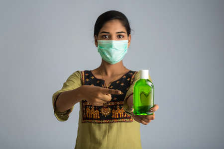 Portrait of young girl using or showing a sanitizing gel from a bottle for hands cleaning.の写真素材