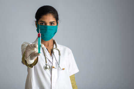 A female doctor with a stethoscope is holding and showing an Injection or Syringe.の写真素材