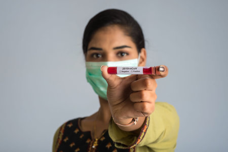 Woman holding a test tube with blood sample for coronavirus or 2019-nCoV analyzing.