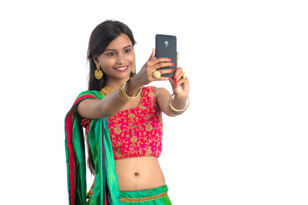 Young Indian girl using a mobile phone or smartphone, talking selfie or talking on video chat...
