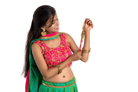 Beautiful girl showing Rakhi on occasion of Raksha bandhan on a white background. Sister tie Rakhi as symbol of intense love for her brother.の写真素材