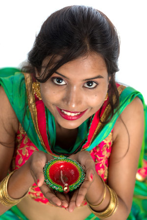 Portrait of a Indian Traditional Girl holding Diya, Girl Celebrating Diwali or Deepavali with holding oil lamp during festival of light on white backgroundの写真素材
