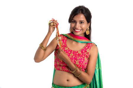Beautiful girl showing Rakhi on occasion of Raksha bandhan on a white background. Sister tie Rakhi as symbol of intense love for her brother.の写真素材