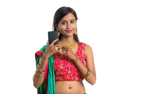 Young Indian traditional girl using a mobile phone or smartphone isolated on a white backgroundの写真素材