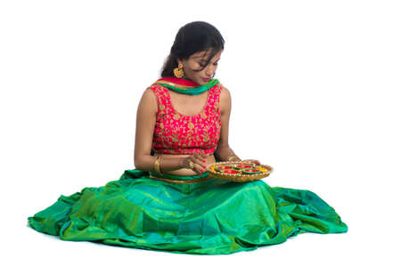 Portrait of a Indian Traditional Girl holding Diya, Girl Celebrating Diwali or Deepavali with holding oil lamp during festival of light on white backgroundの写真素材