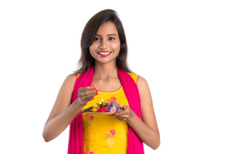 Beautiful Indian young girl holding pooja thali or performing worship on a white backgroundの写真素材