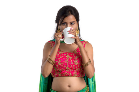 Beautiful young girl with cup of tea or coffee posing on white backgroundの写真素材