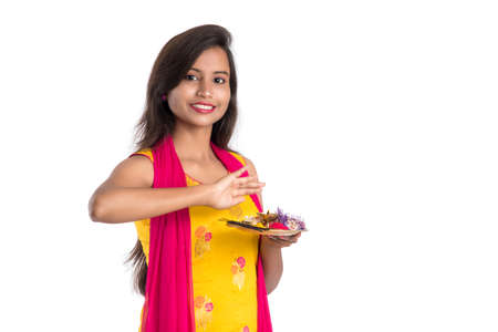 Beautiful Indian young girl holding pooja thali or performing worship on a white backgroundの写真素材