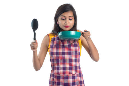 Young Indian woman holding kitchen utensil (spoon, stapula, ladle, and pan, etc.) on a white backgroundの写真素材