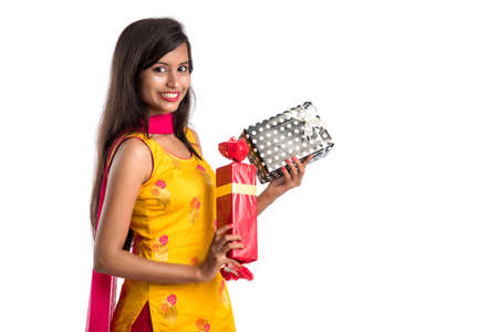 Portrait of young happy smiling Indian Girl holding gift boxes on a white background.の写真素材