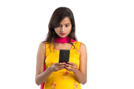 Young Indian girl using a mobile phone or smartphone isolated on a white backgroundの写真素材