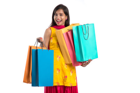 Beautiful Indian young girl holding and posing with shopping bags on a white backgroundの写真素材