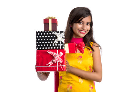 Portrait of young happy smiling Indian Girl holding gift boxes on a white background.の写真素材