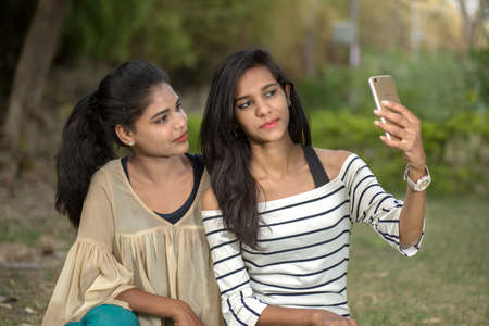 Two beautiful female friends taking selfie with smartphone in outdoors.の写真素材