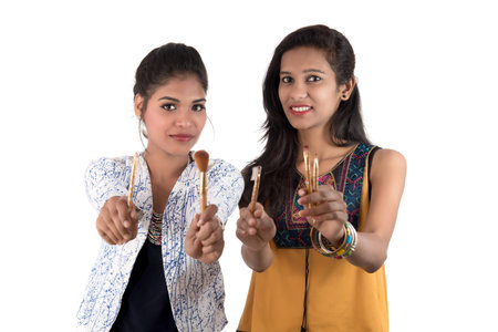 Beautiful young girls enjoying with makeup brushes isolated on whiteの写真素材