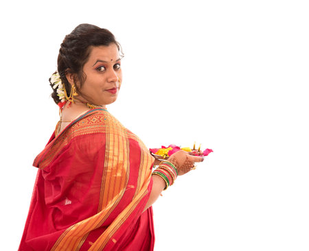 Portrait of a Indian Traditional Girl holding pooja thali with diya during festival of light on white background. Diwali or deepavaliの写真素材