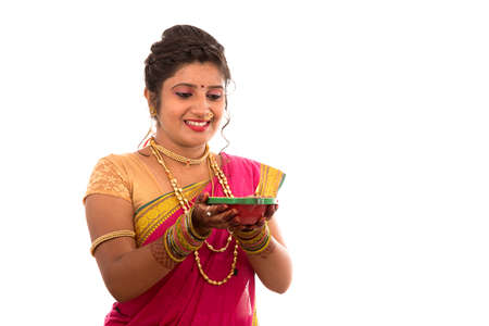 Portrait of a Indian Traditional Girl holding pooja thali with diya during festival of light on white background. Diwali or deepavaliの写真素材