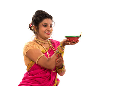 Portrait of a Indian Traditional Girl holding diya, Diwali or deepavali photo with female hands holding oil lamp during festival of light on white backgroundの写真素材