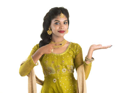Portrait of cheerful Indian traditional young woman presenting something, showing copy space on her palm on a white backgroundの写真素材
