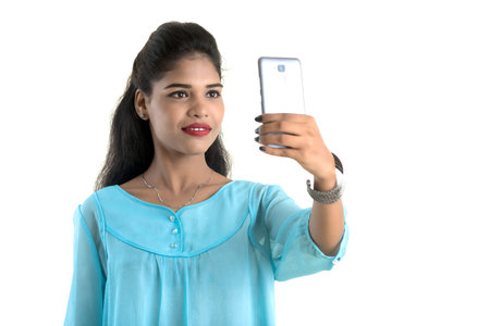 Young Indian girl using a mobile phone or smartphone isolated on a white background