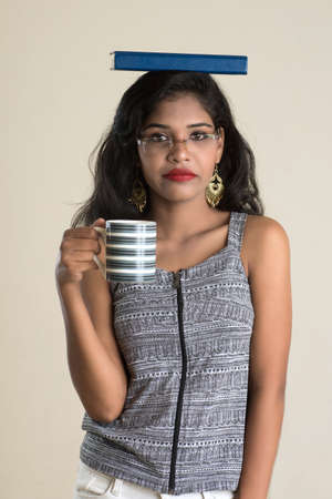 Beautiful young girl with book and cup of tea or coffee posing on a white background.の写真素材