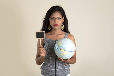 Portrait of young Girl holding and posing with a world globe and small black board