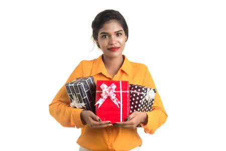 Portrait of young happy smiling Indian Girl holding gift boxes on a white background.の写真素材