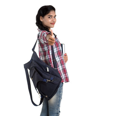young Indian woman with backpack standing and holding notebooks, posing on a white background.