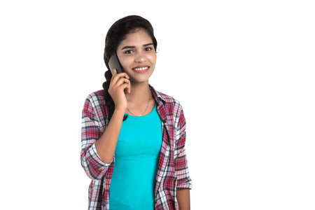 Young Indian girl using a mobile phone or smartphone isolated on a white backgroundの写真素材