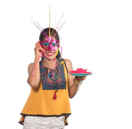 Beautiful young girl holding powdered color in plate with carnival mask on the occasion of Holi festival.の写真素材