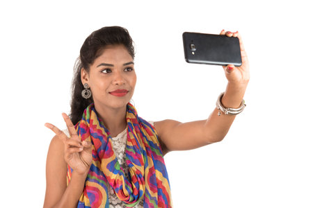 Young Indian girl using a mobile phone or smartphone isolated on a white backgroundの写真素材