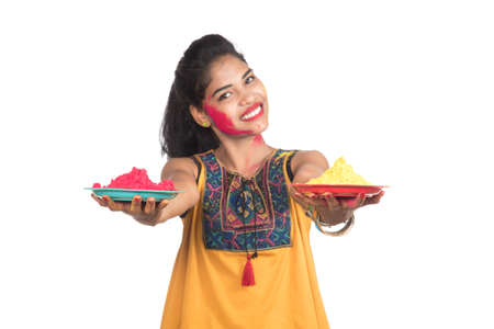 Beautiful young girl holding powdered color in plate on the occasion of Holi festival.の写真素材