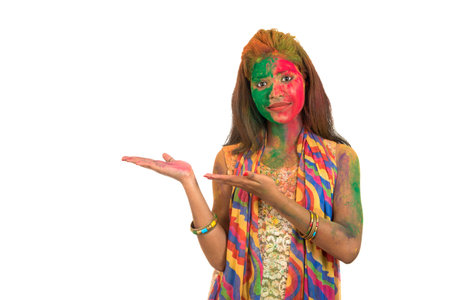 Young girl with a colorful face holding and presenting something on the hand with a happy smiling on occasion of Holi festival. Festival and technology concept.の写真素材