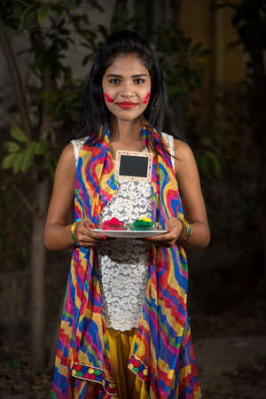 Young girl holding small board and powdered color on the occasion of Holi festival.の写真素材