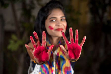 Young girl showing colorful palm and celebrating Holi with color splashの写真素材