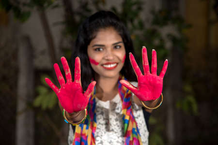 Young girl showing colorful palm and celebrating Holi with color splashの写真素材