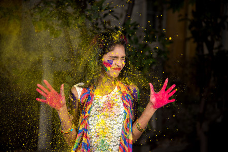 Young girl showing colorful palm and celebrating Holi with color splashの写真素材